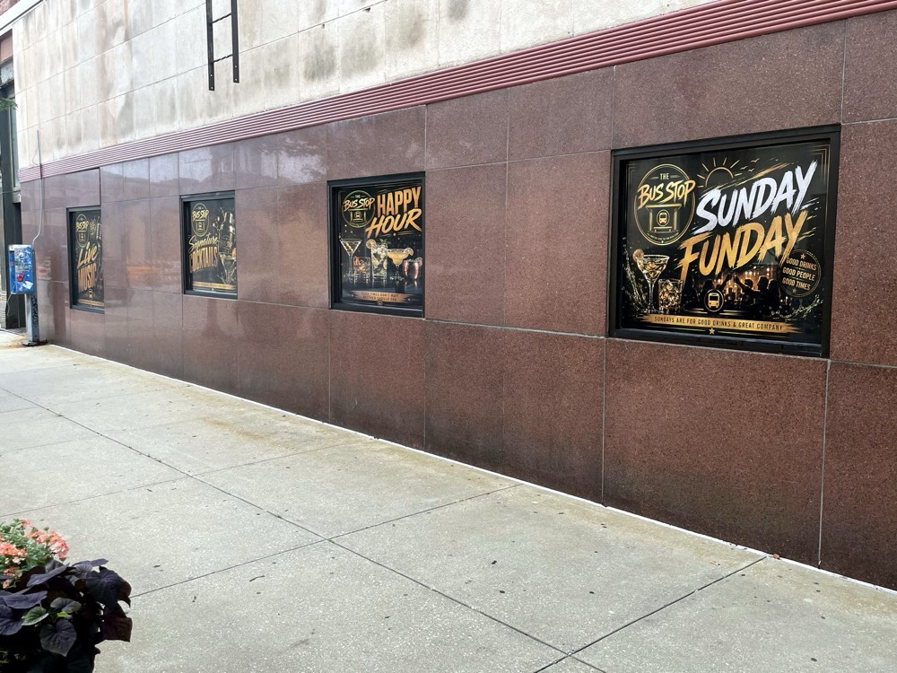 A row of gold-and-black printed window decals along a downtown bar's windows