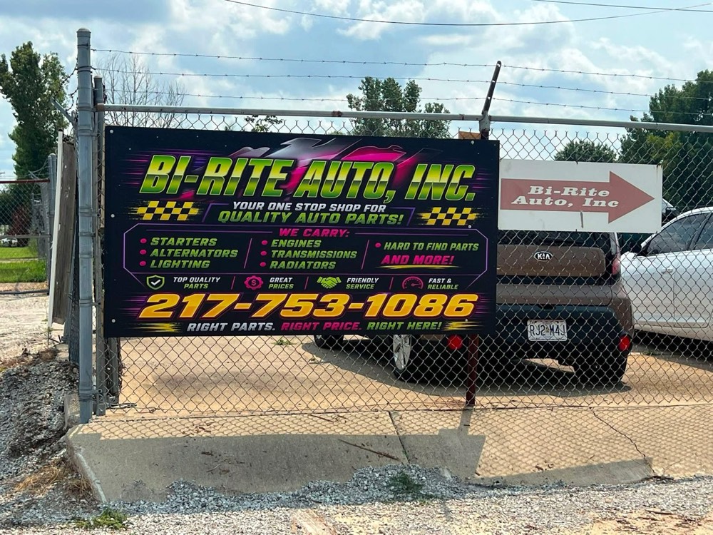 Large banner mounted on a fence at a local auto business