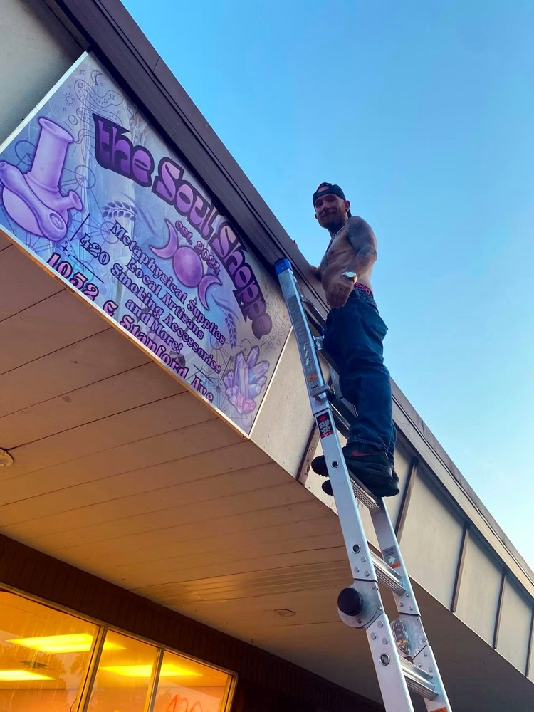 Schafer Services installing signage up a ladder